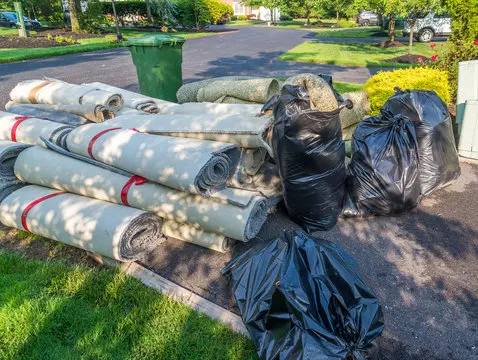 Rolled carpet and bagged debris ready for removal by Mako Property Solutions